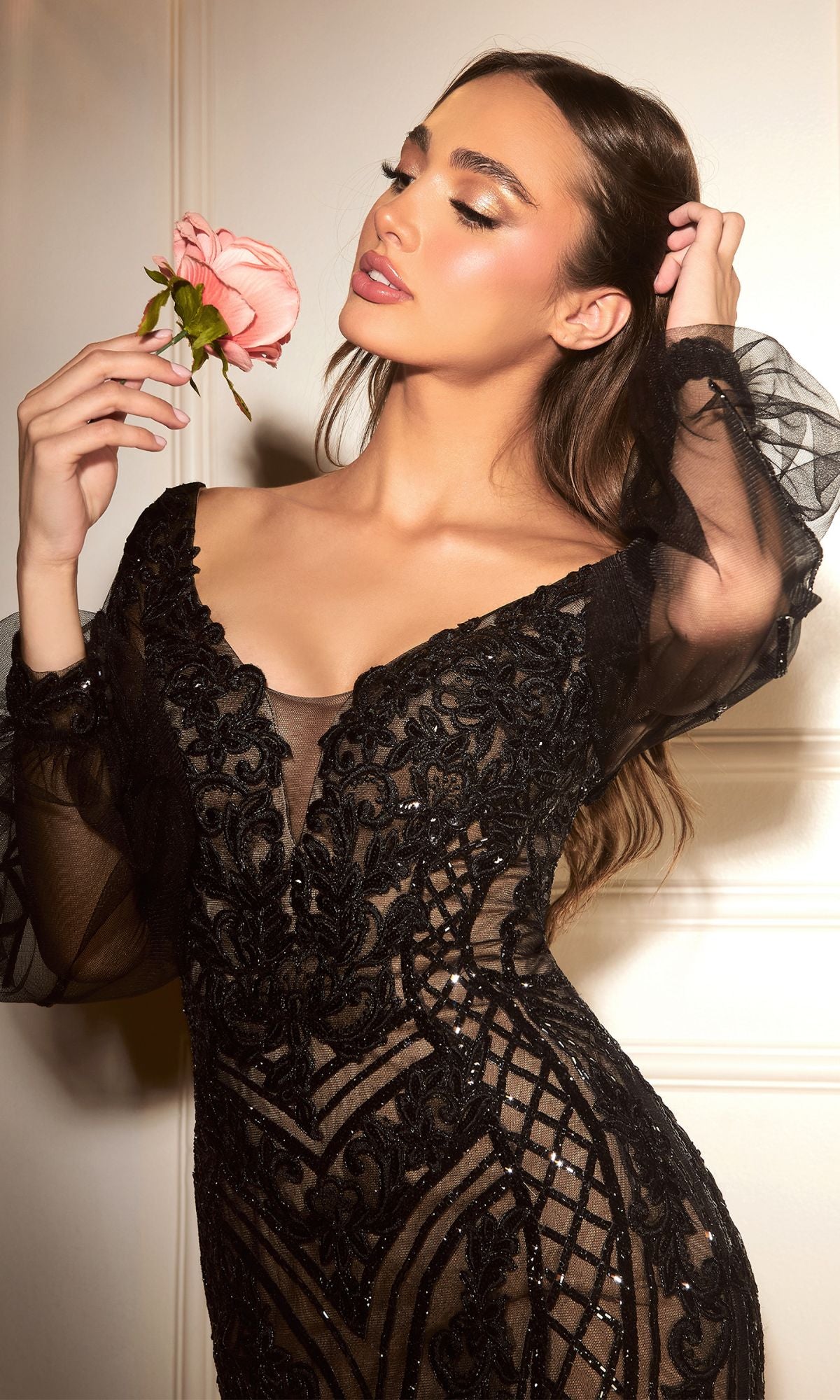 Woman in the Long-Sleeve Long Embellished Formal Dress CD864 poses against a cream backdrop, holding a pink rose near her face with eyes closed, head tilted back.